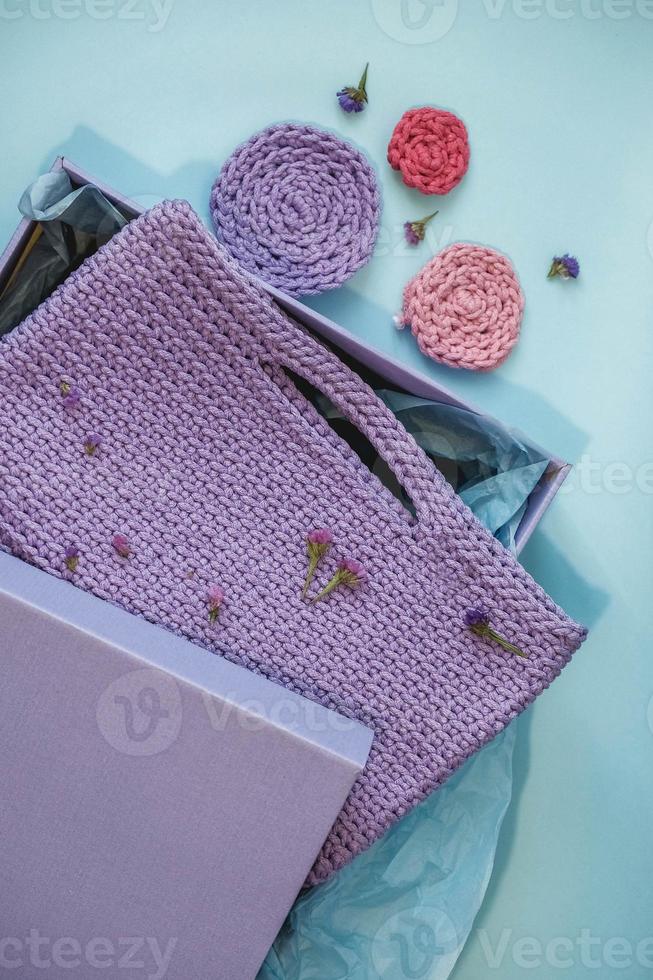 borsa a maglia viola fatta a mano in una scatola di carta su sfondo blu foto