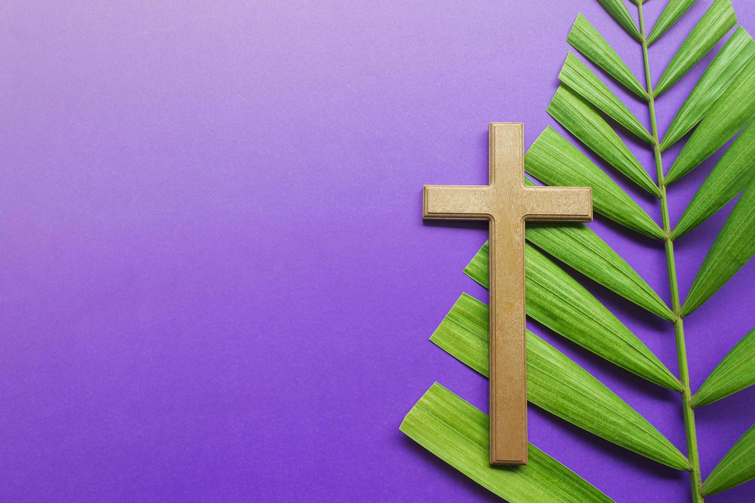 croce e foglie di palma su sfondo viola. concetto di stagione quaresimale. foto