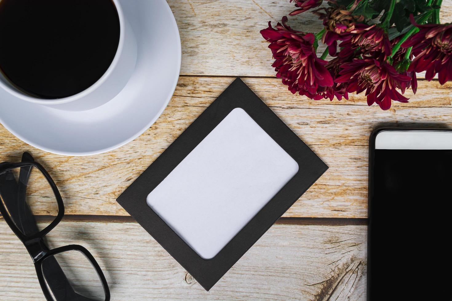 cornice lavagna con fiori di dalia, tazza di caffè bianca e smartphone su scrivania in legno. direttamente sopra, disteso, copia spazio. foto
