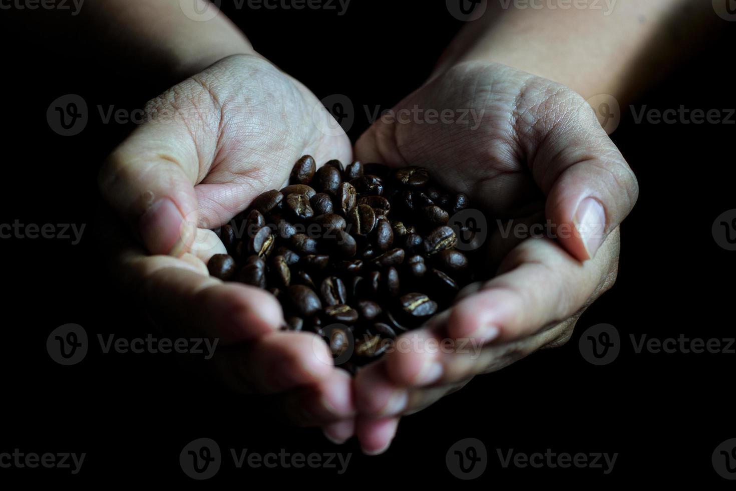 chicchi di caffè nelle mani del cuore a forma di su tavola di legno in stile scuro foto
