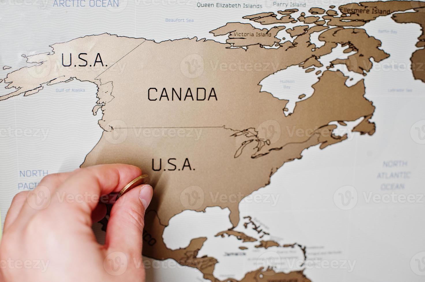 scratch mappa di viaggio del mondo. mano dell'uomo cancella gli Stati Uniti con la moneta. foto
