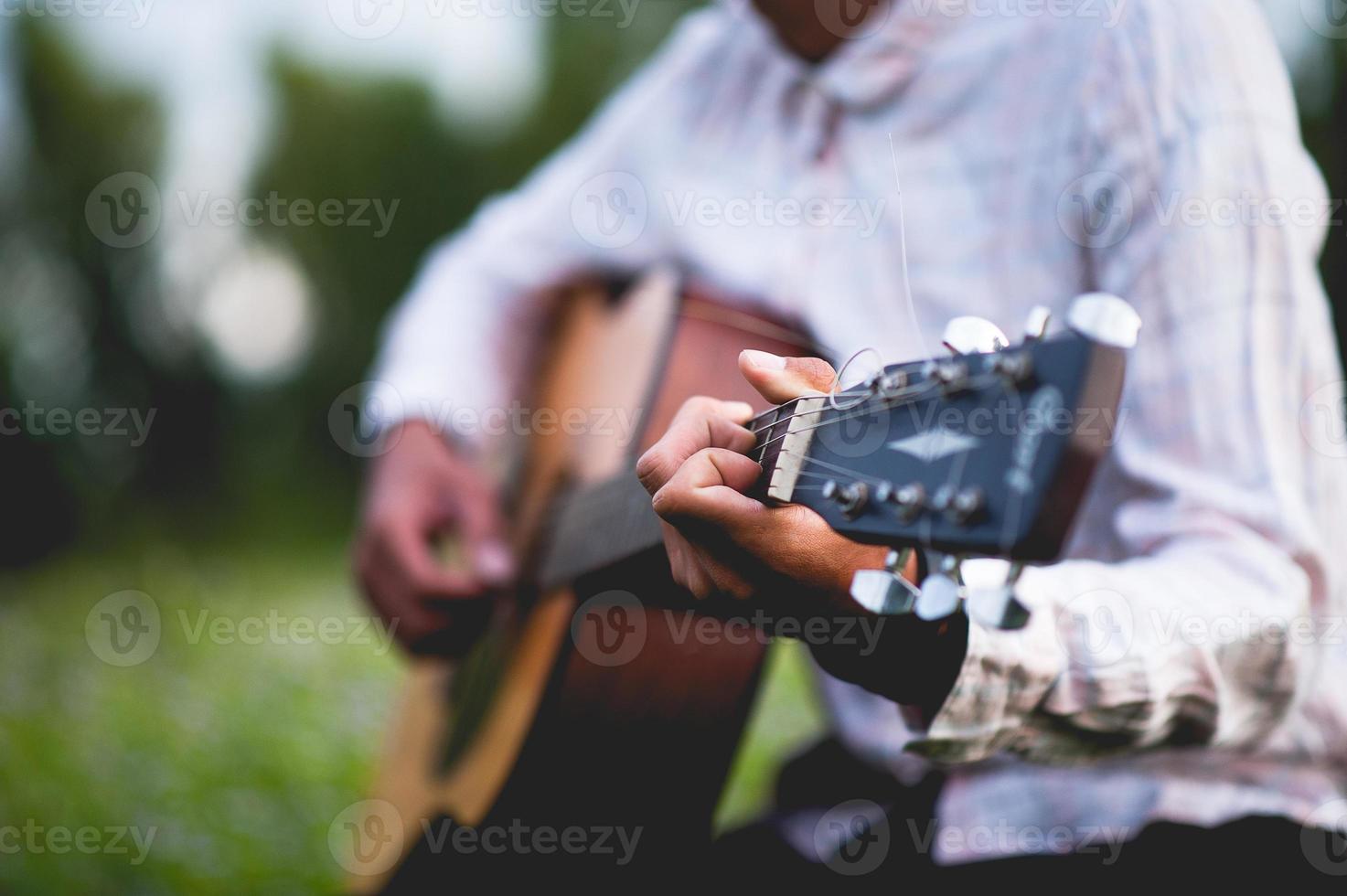 la mano dell'uomo suona la chitarra acustica, suona la chitarra in giardino da solo, felicemente e ama la musica. foto