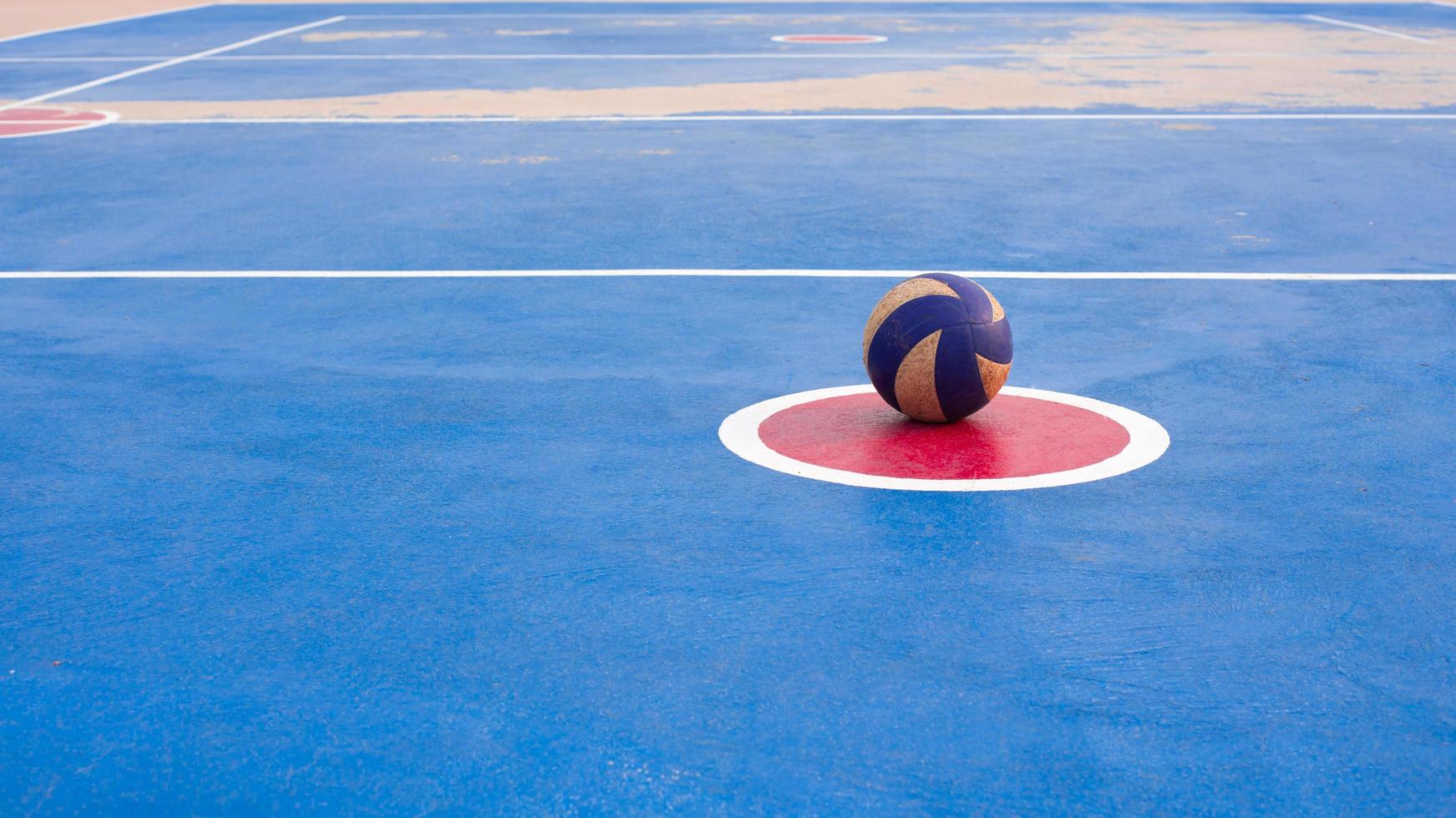 una vecchia palla da pallavolo che era stata lasciata al centro del cerchio rosso attorno al terreno era quattro blu. foto