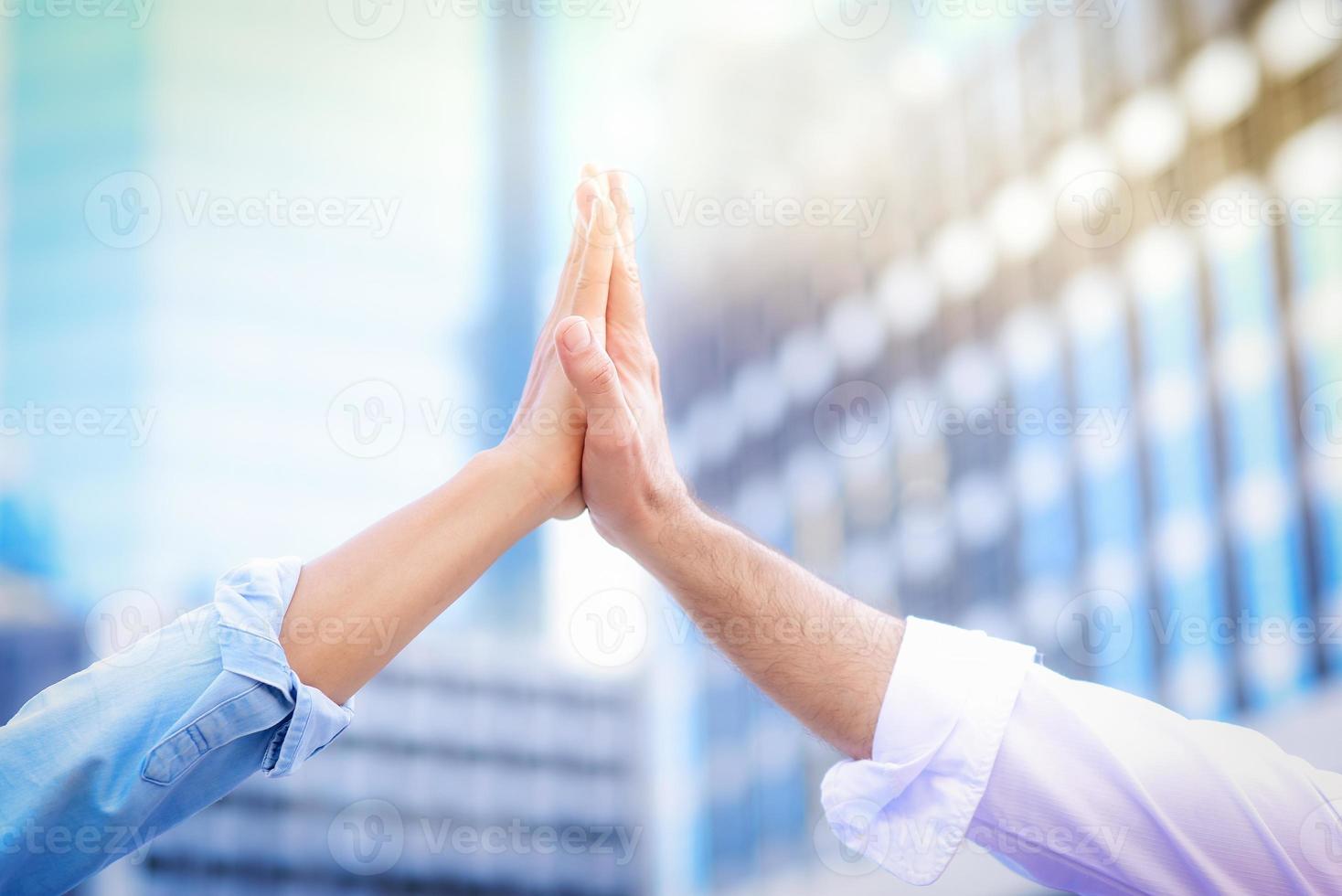 primo piano di entrambe le mani che danno il cinque l'una all'altra con uno sfondo sfocato dell'edificio, nel concetto di collaborazione aziendale di successo e lavoro di squadra foto