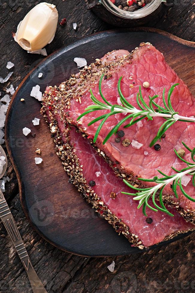 bistecca di manzo cruda con spezie e un rametto di rosmarino foto