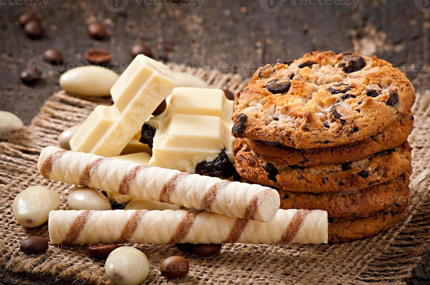 cioccolato bianco, mandorle e biscotti su fondo di legno foto