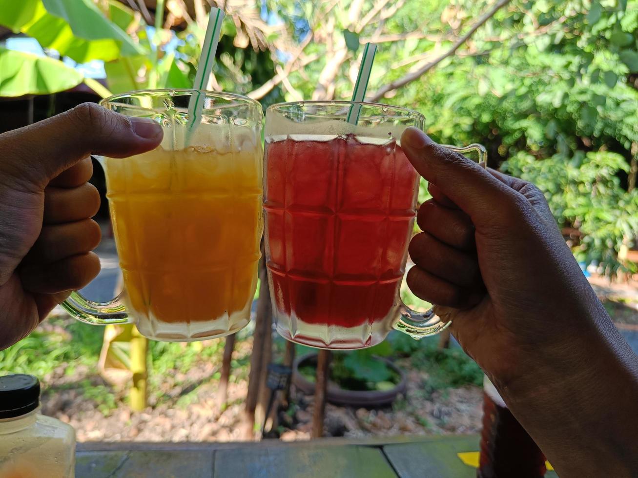 gli amici applaudono un bicchiere di succo d'arancia e succo di rosella per rinfrescarsi in estate, sfocare lo sfondo foto