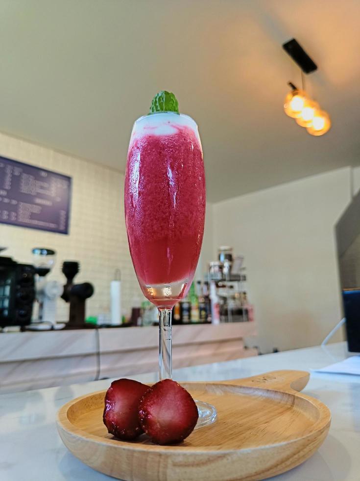 bicchiere di frullato di fragole fresche e fragole fresche sul piatto di legno. concetto di cibi e bevande sani. foto