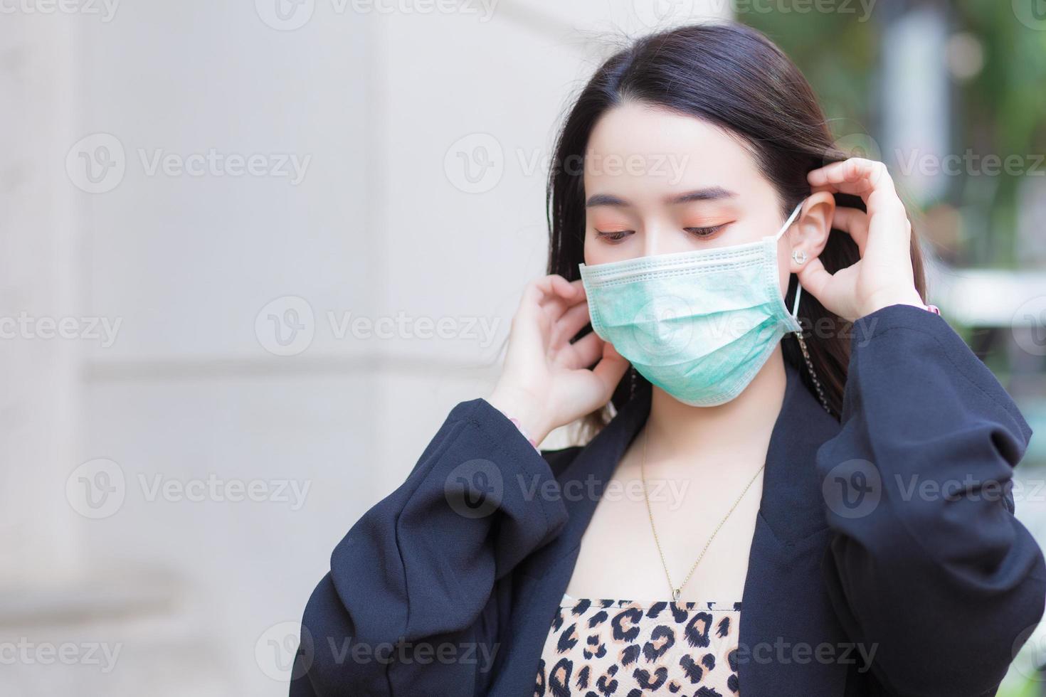 bella ragazza asiatica in cappotto nero indossa una maschera medica per proteggere il sistema respiratorio dall'infezione da coronavirus-19 covid-19. foto