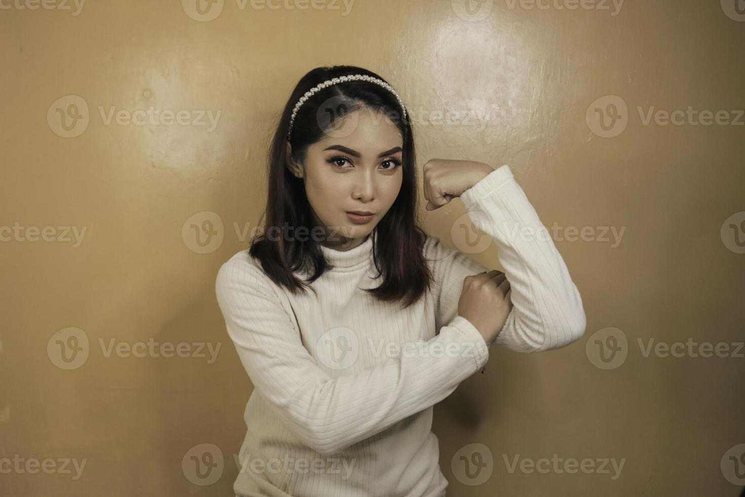 splendida giovane donna asiatica forte con camicia bianca che mostra bicipiti e sorridente. concetto forte della ragazza indonesiana. foto