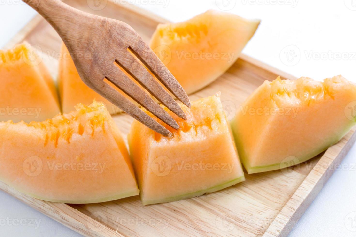 melone succoso del melone con la forcella su un piatto di legno foto