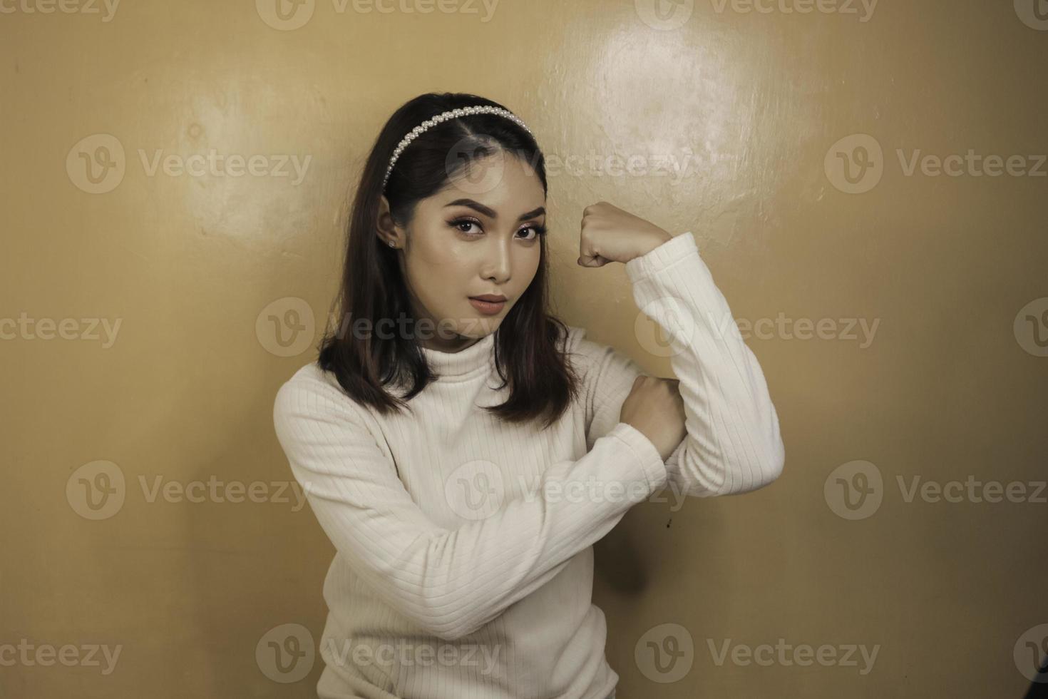 splendida giovane donna asiatica forte con camicia bianca che mostra bicipiti e sorridente. concetto forte della ragazza indonesiana. foto