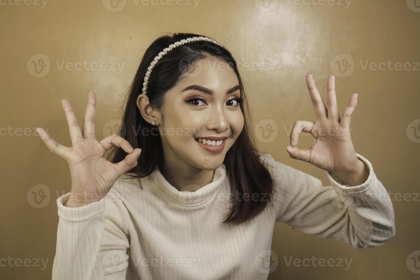 la giovane donna asiatica è selfie con la faccia sorridente felice e il segno giusto vicino alla bocca guarda la telecamera foto