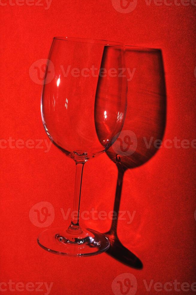 natura morta minimalista, bicchiere di vino su sfondo rosso con ombra creativa. foto