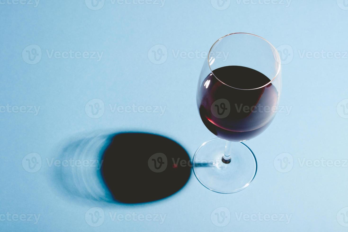 bicchiere di vino rosso su sfondo blu con ombra scura. foto