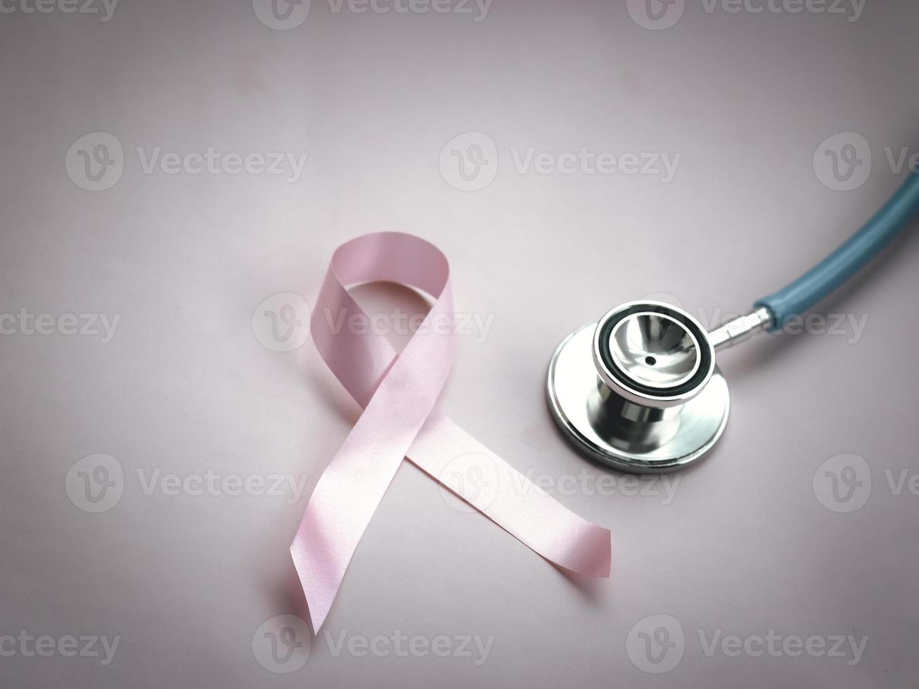 nastro rosa di consapevolezza del cancro al seno con stetoscopio medico su sfondo rosa, simbolo di ottobre, concetto di assistenza sanitaria e medicina foto