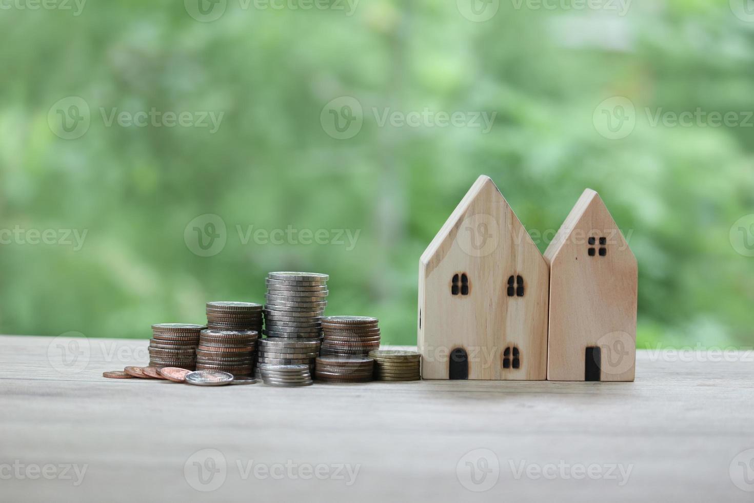 pila di monete e casa di legno su sfondo verde sfocato del giardino, risparmio di denaro e concetto di gestione finanziaria aziendale. foto