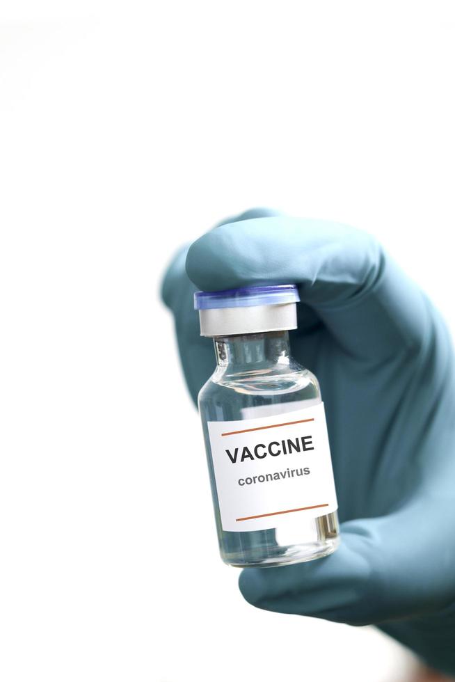 guanti da indossare per le mani che tengono una fiala di vetro contenente vaccino medico liquido utilizzato per sparare per il trattamento di iniezione su sfondo bianco, vaccinazione e immunizzazione per prevenire l'epidemia di coronavirus foto