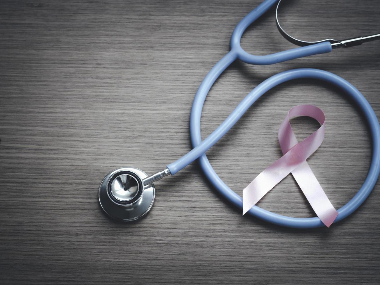 nastro rosa di consapevolezza del cancro al seno con stetoscopio medico su sfondo di legno, simbolo di ottobre, concetto di assistenza sanitaria e medicina foto