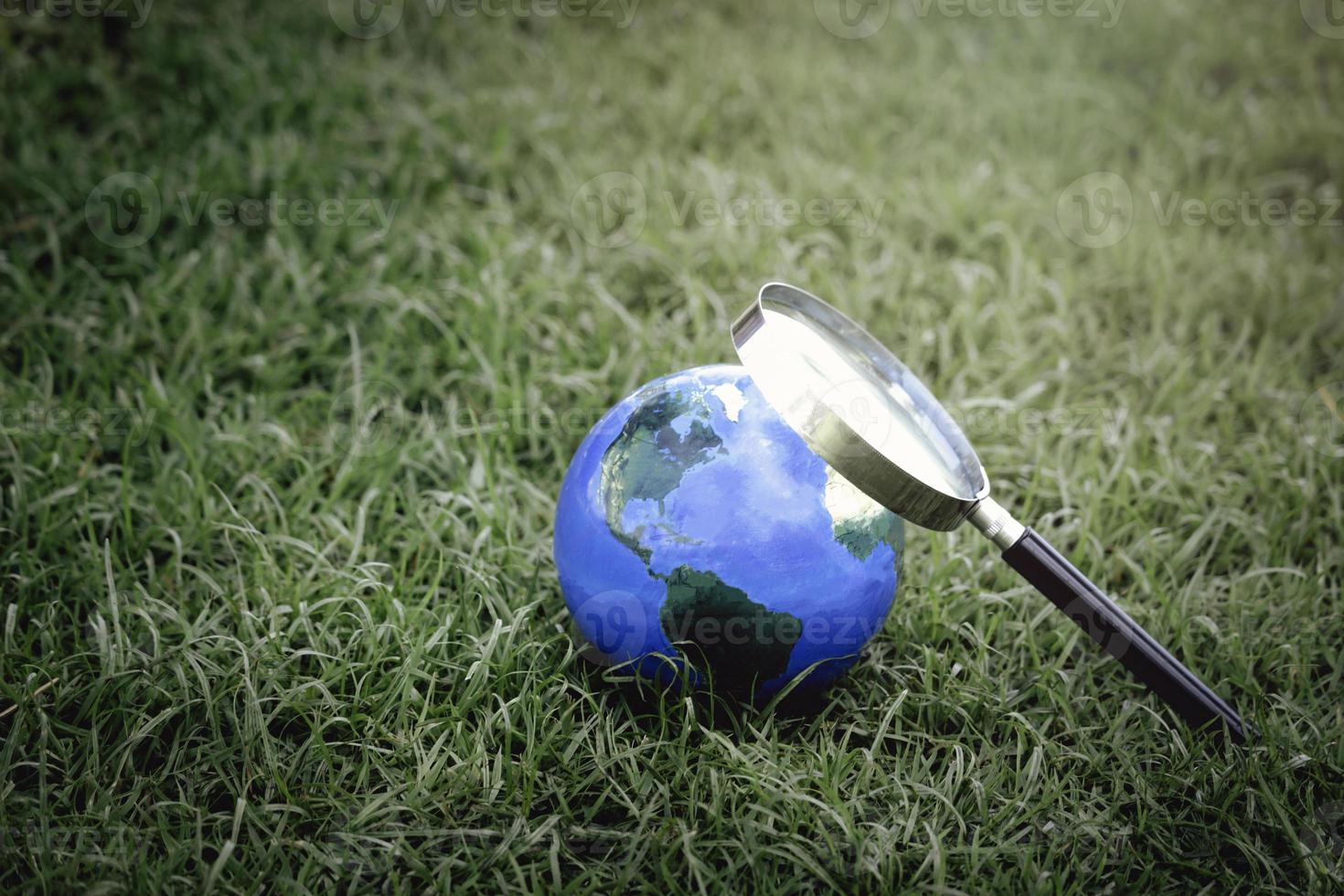 globo terrestre con lente d'ingrandimento sull'erba verde, alla scoperta di nuove cose sul nostro pianeta, interessato alla natura e al mondo foto