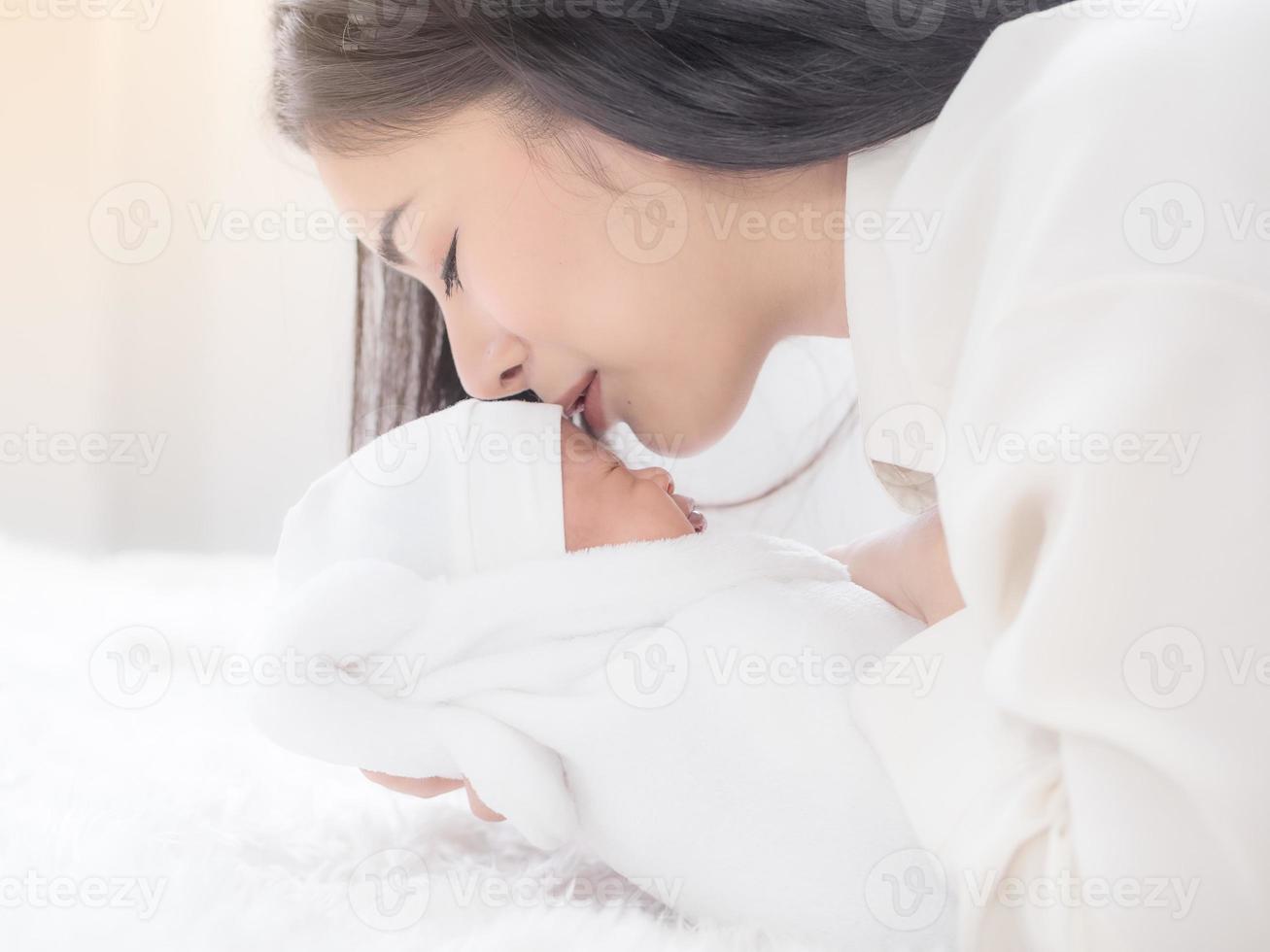 una bella donna asiatica portava il suo neonato e baciava con felicità foto