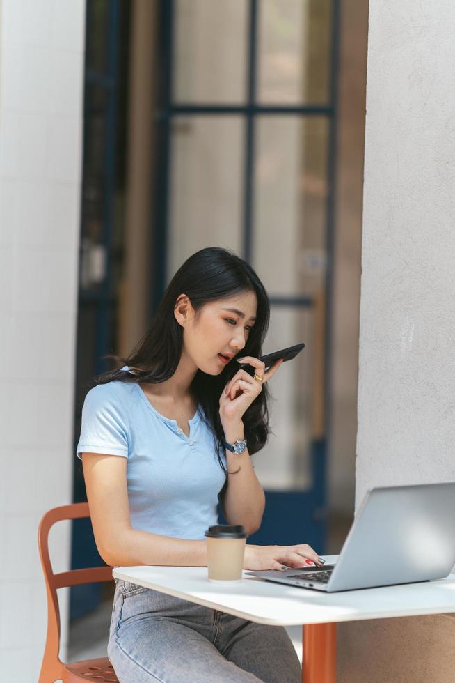 ritratto di bella donna asiatica seduta all'aperto al ristorante caffetteria durante l'estate, utilizzando computer portatile e smartphone con tecnologia wireless intelligente, rilassante pausa caffè al ristorante caffetteria. foto