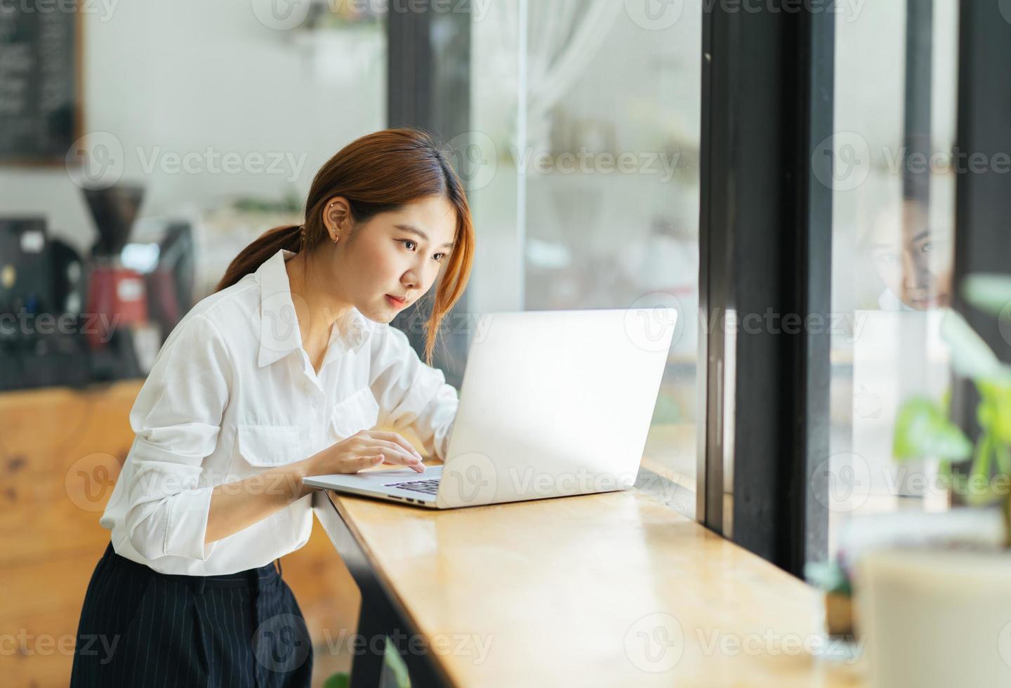 bella giovane donna di affari asiatica sveglia nel caffè, usando il computer portatile. foto