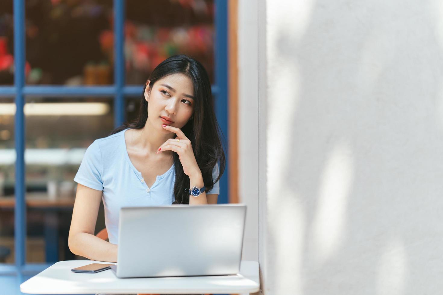 ritratto di bella donna asiatica seduta all'aperto al ristorante caffetteria durante l'estate, utilizzando computer portatile e smartphone con tecnologia wireless intelligente, rilassante pausa caffè al ristorante caffetteria. foto