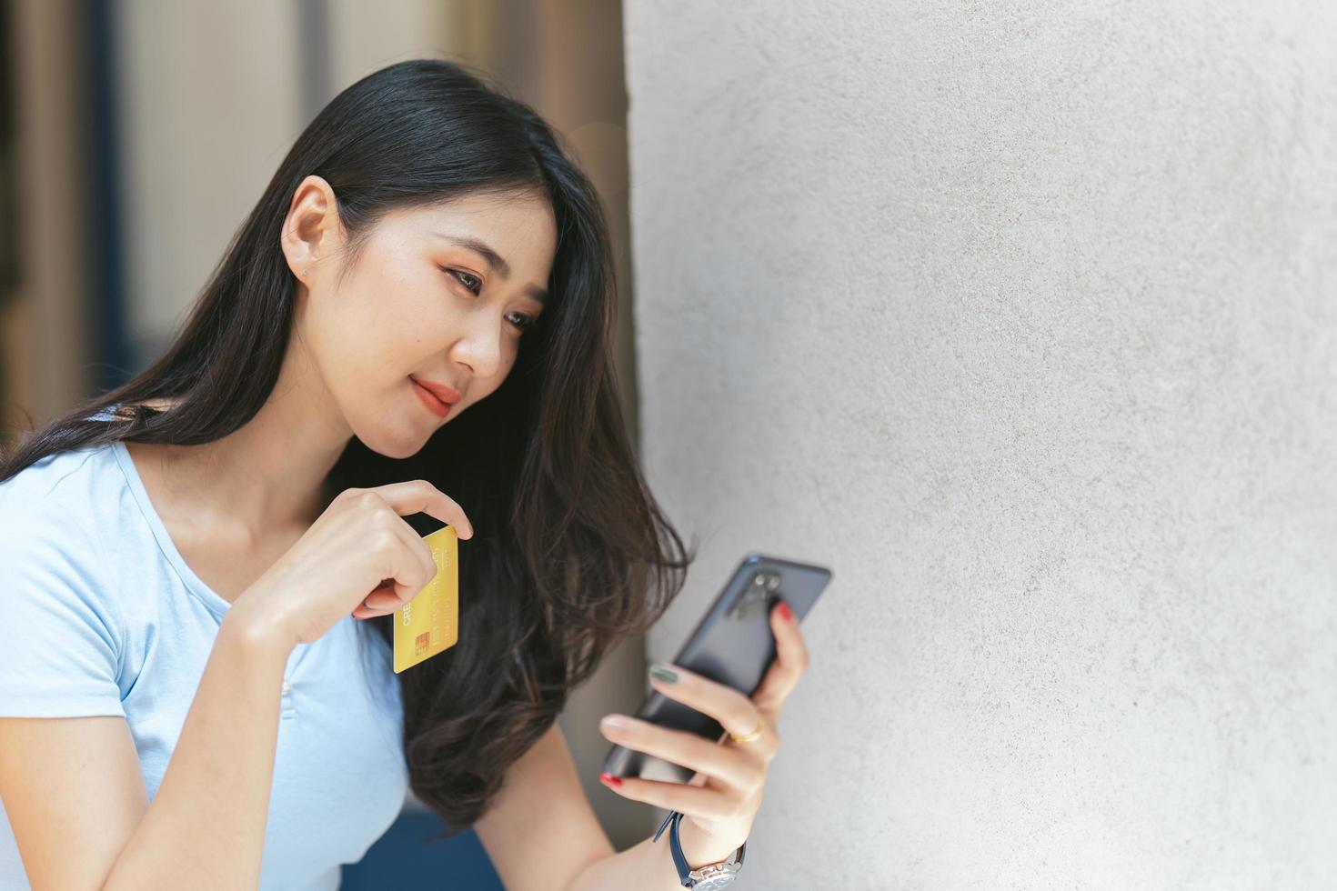 concetto di banca online. ritratto di felice giovane donna asiatica con smartphone e carta di credito seduti al bar, donne asiatiche sorridenti che si divertono a effettuare pagamenti da casa. foto