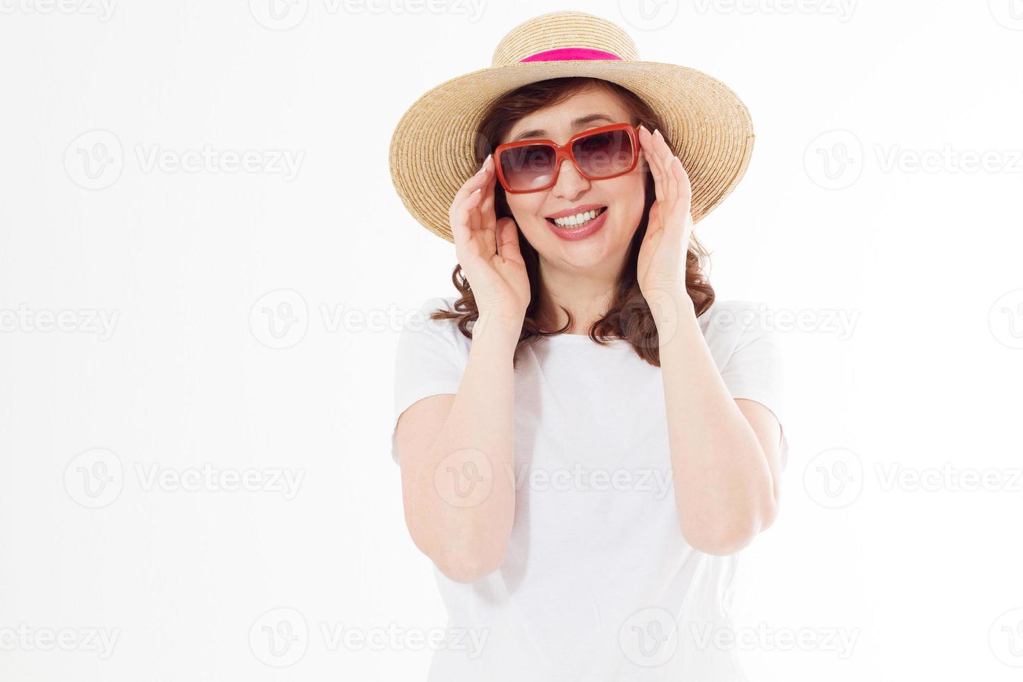 donna felice di mezza età in cappello estivo, occhiali da sole. protezione della pelle estiva, accessori moda. femmina in maglietta bianca modello in bianco isolata. copia spazio sullo sfondo. vacanze e vacanze al mare. foto