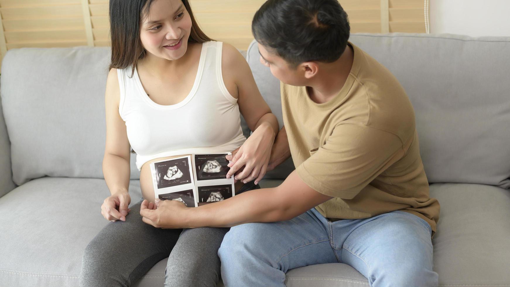 giovane donna incinta con marito che tiene una foto ad ultrasuoni del neonato, della maternità e del concetto di famiglia