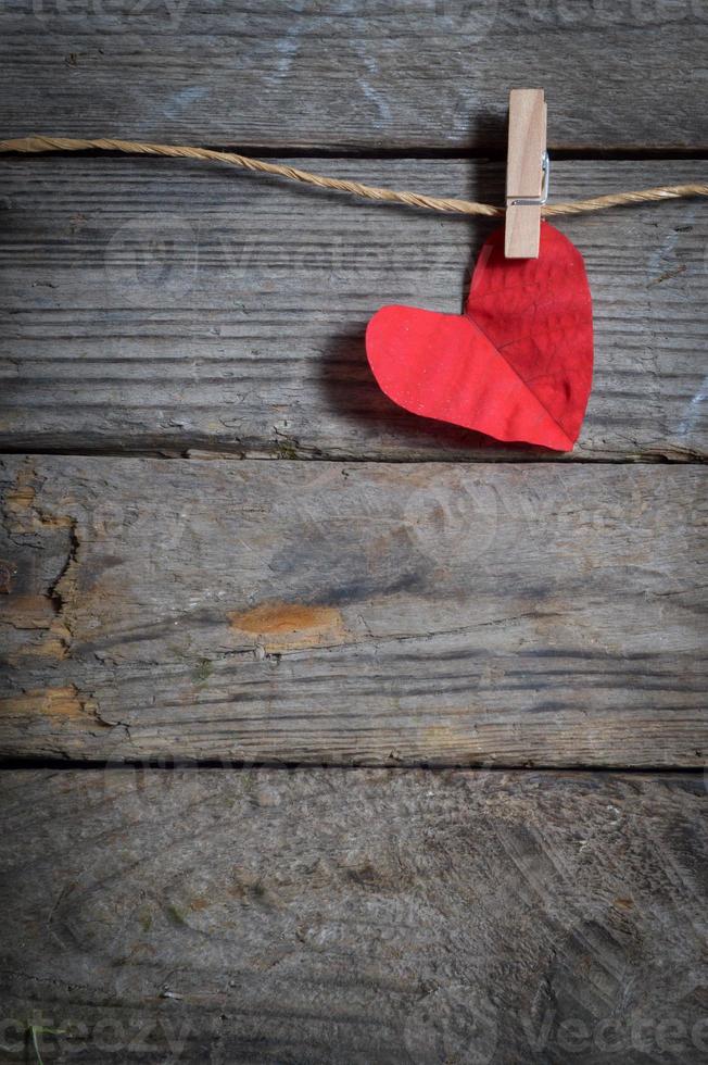 cuore rosso appeso al bucato. sullo sfondo di legno vecchio. foto