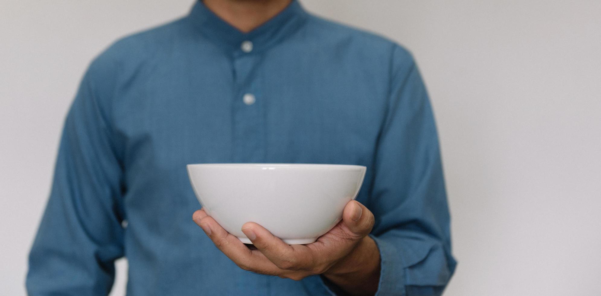 giovane uomo bello che indossa una camicia azzurra con in mano una tazza di colazione calda. foto