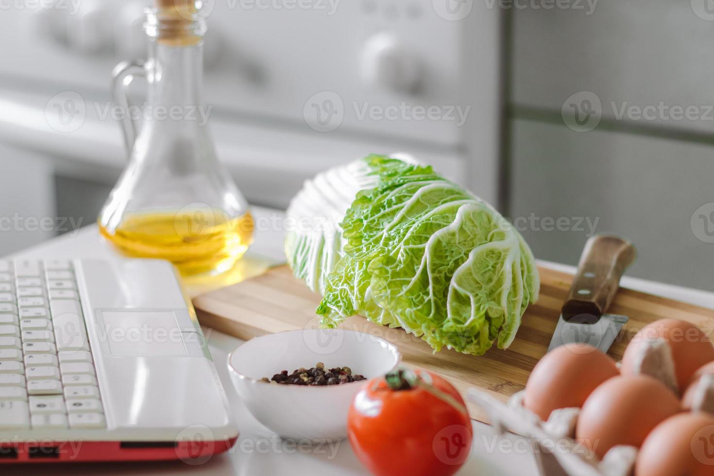 cucina in linea. preparare l'insalata usando il ricettario digitale. verdure fresche e laptop foto