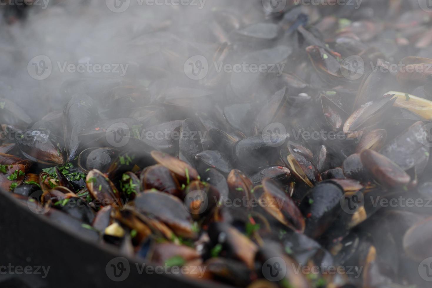 primo piano di cozze cotte in un festival di cibo di strada, pesce pronto da mangiare fotografato con messa a fuoco morbida foto