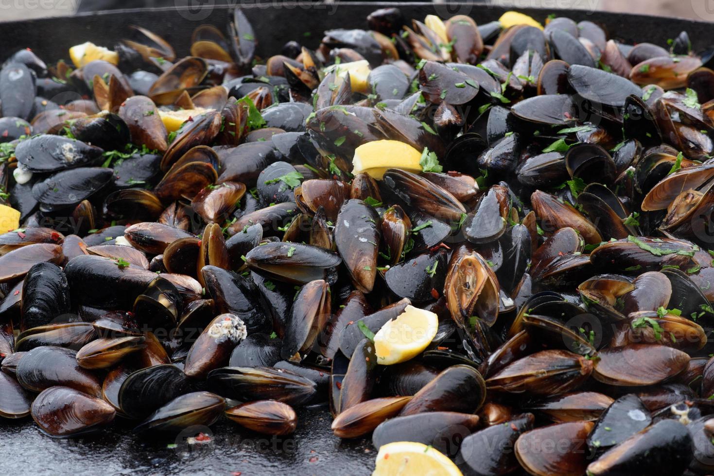 primo piano di cozze cotte in un festival di cibo di strada, pesce pronto da mangiare fotografato con messa a fuoco morbida foto