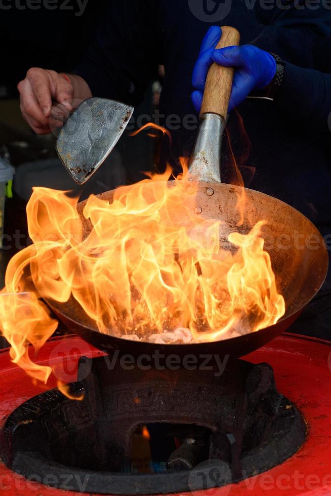 uno chef prepara cibo cinese a un festival del cibo di strada. foto
