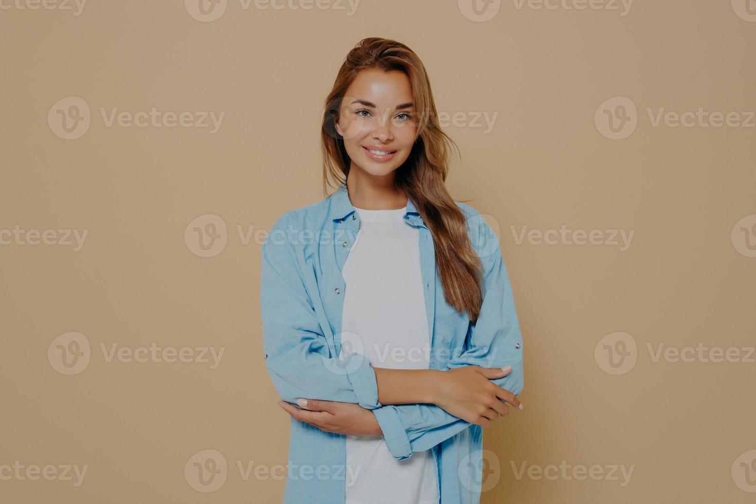 attraente giovane donna con le braccia incrociate su sfondo beige foto