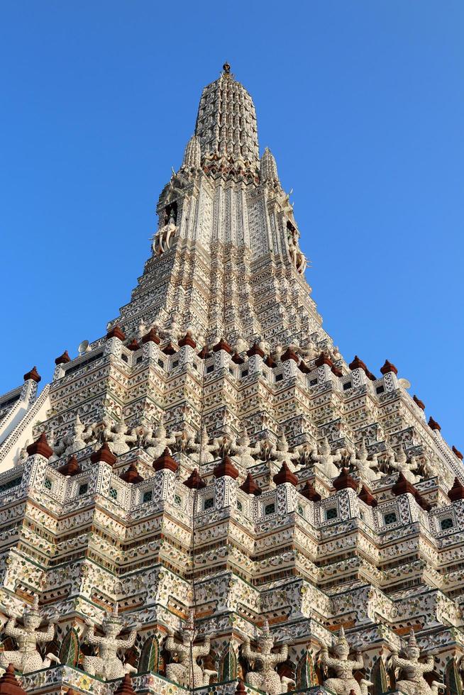 pagoda bianca nel tempio di wat arun e cielo blu. statue antiche intorno alla base della pagoda. wat arun è un antico monumento in Thailandia. foto