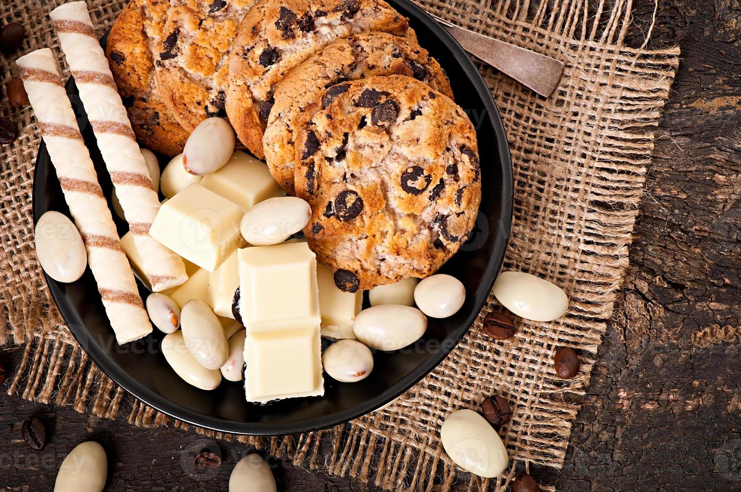 cioccolato bianco, mandorle e biscotti su fondo di legno foto
