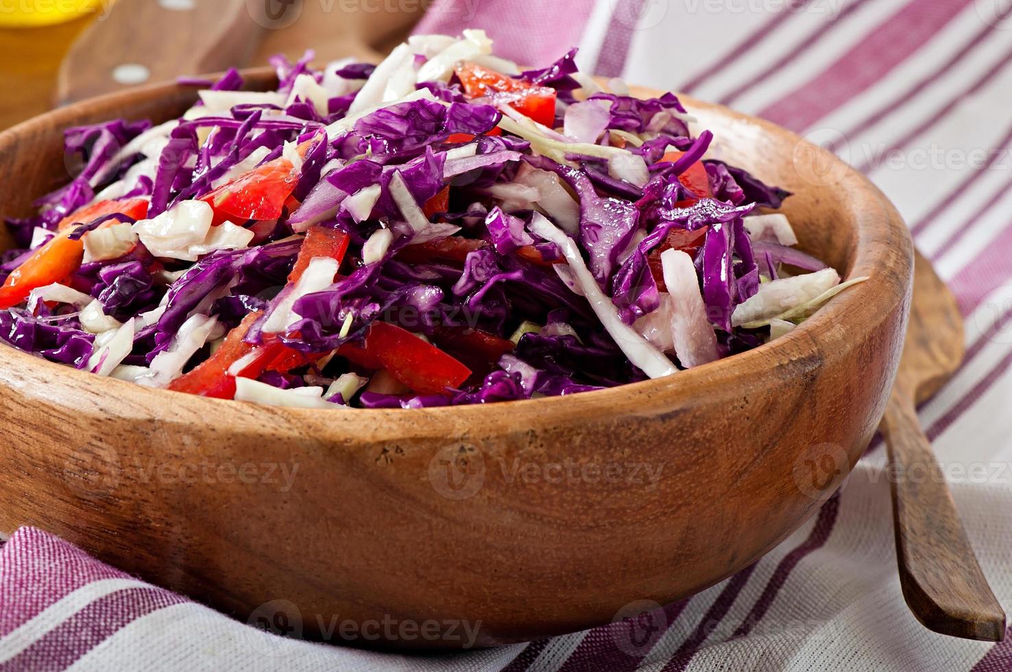 insalata di cavolo cappuccio rosso e bianco e peperone rosso dolce, condita con succo di limone e olio d'oliva in una ciotola di legno foto