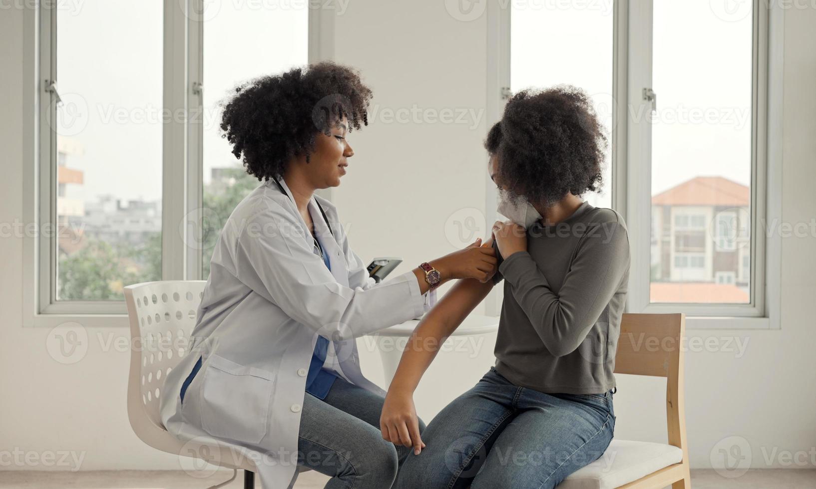 il medico afroamericano sta applicando il cerotto sulla spalla di un bambino dopo essere stato vaccinato. maniche di apertura per vaccinare contro l'influenza o l'epidemia nell'assistenza sanitaria e nel concetto di vaccinazione. foto