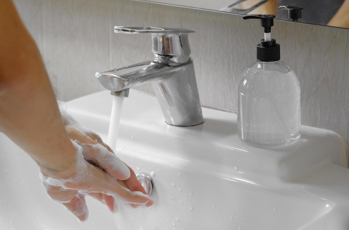 uomo asiatico lavarsi le mani con sapone nel lavandino del bagno. igiene e concetto di prevenzione covid-19, spazio di copia. foto