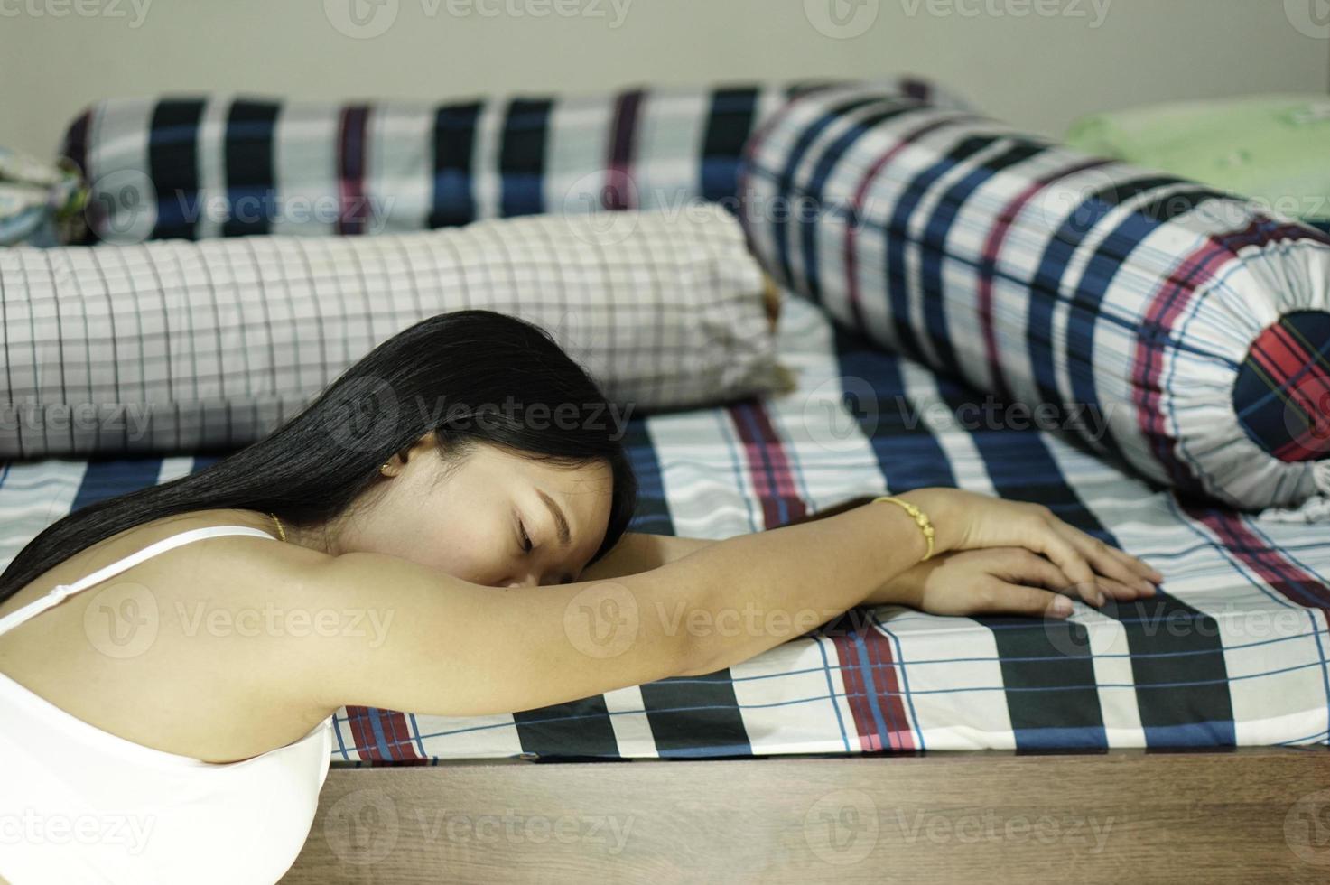 donna asiatica seduta in camera da letto a piangere foto