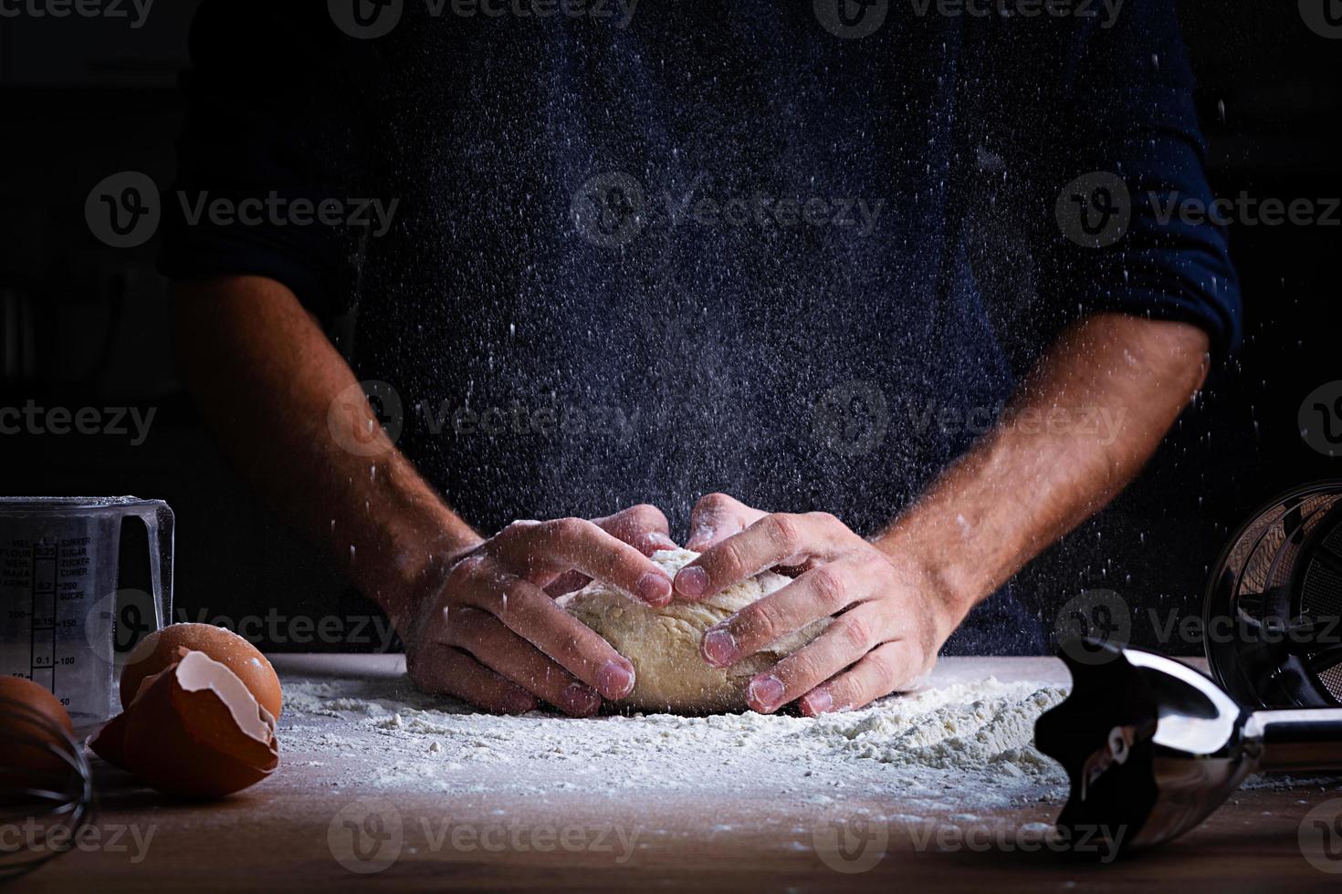 mani maschili che producono pasta per pizza, gnocchi o pane. concetto di cottura. foto