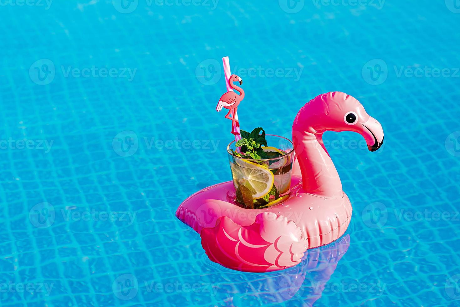 fresco cocktail mojito sul giocattolo gonfiabile del fenicottero rosa in piscina. concetto di vacanza. foto