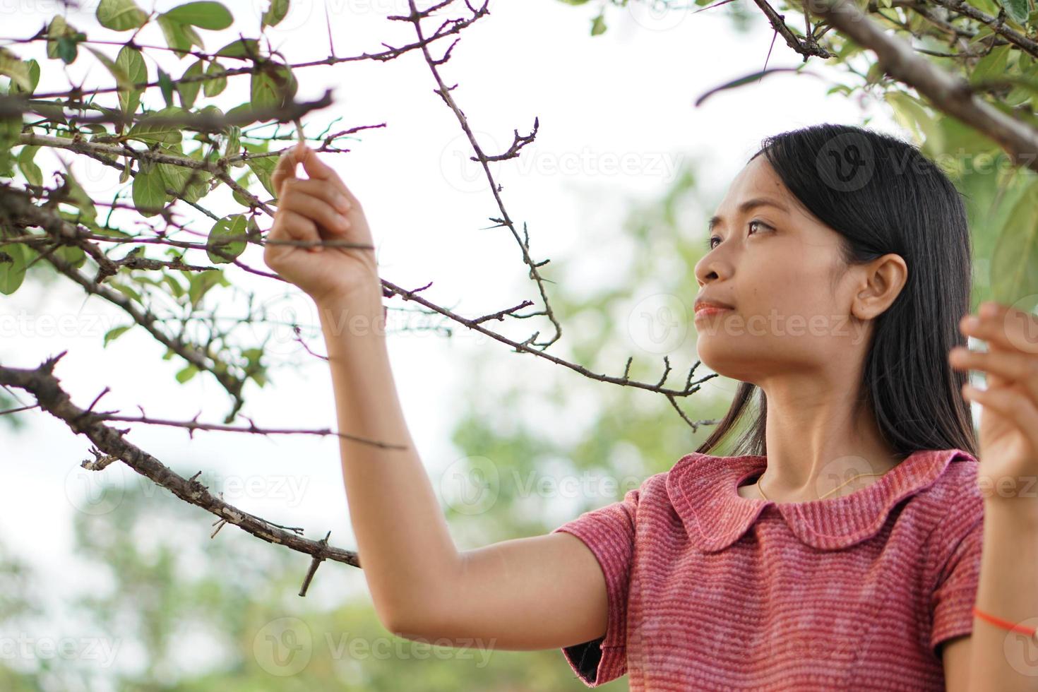 donna asiatica che sorride felicemente alza la mano sullo sfondo della natura del cielo foto