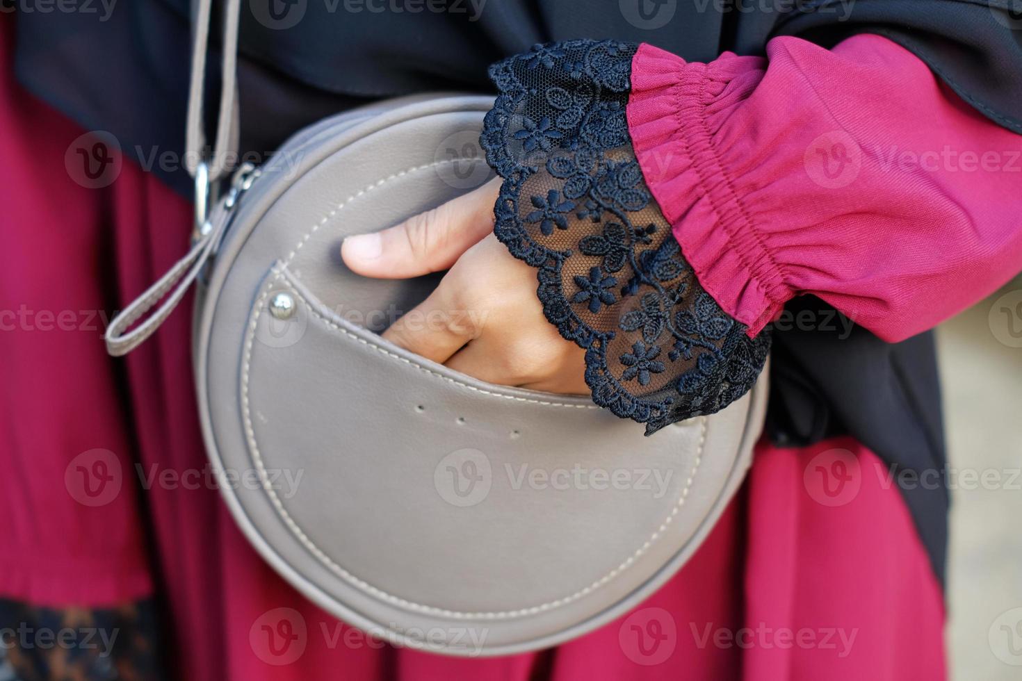 la mano di una donna tiene una borsa a tracolla grigia foto