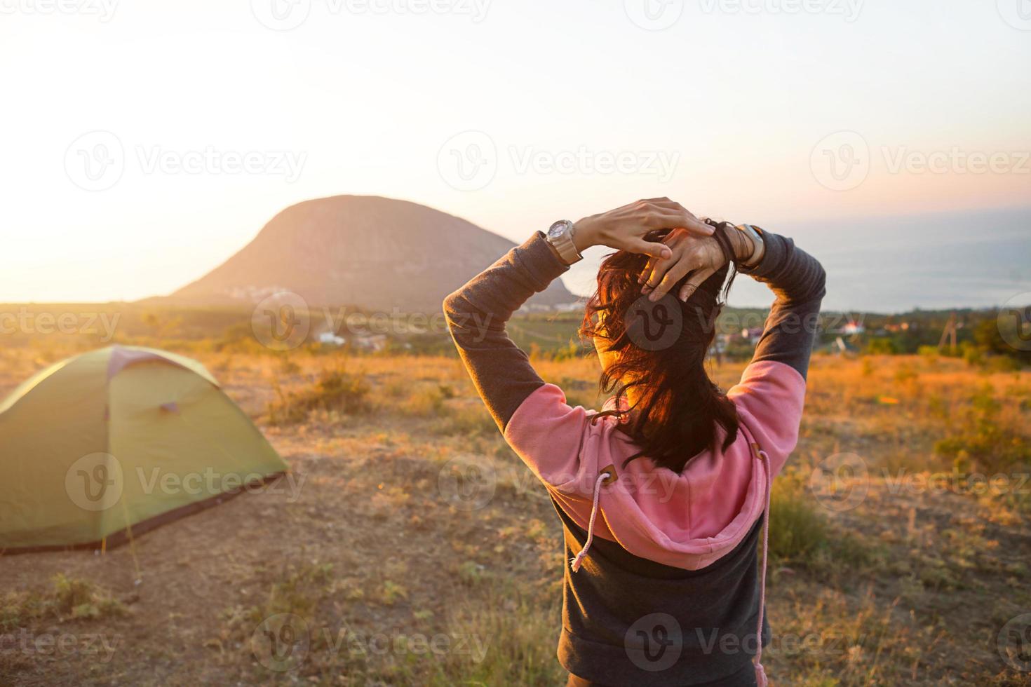 la donna incontra l'alba in montagna, gioisce al sole. vista panoramica sulla montagna e sul mare dall'alto. campeggio, attività all'aperto, escursionismo sportivo in montagna, viaggi in famiglia. ayu-dag, Crimea. foto