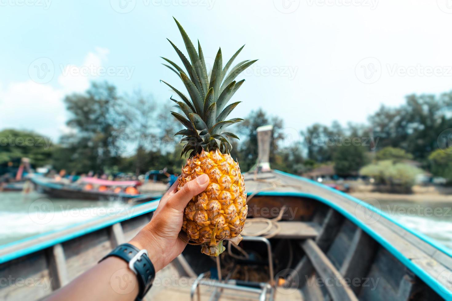 ananas estivo, ananas in mano su una barca in mare foto